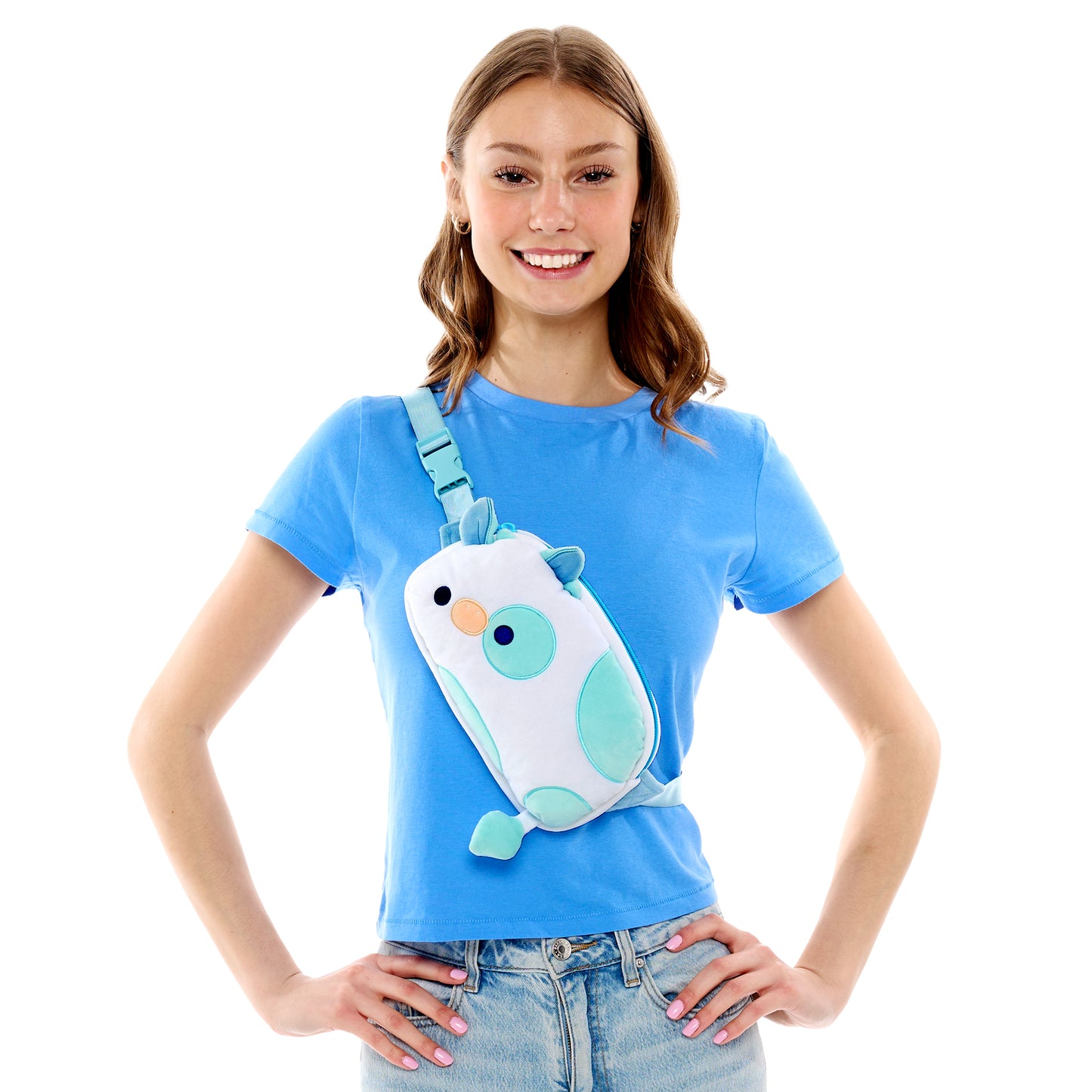 Woman smiling while wearing a blue t-shirt and holding a TeeTurtle Plushiverse Udderly Adorable Plushie Fanny Pack.