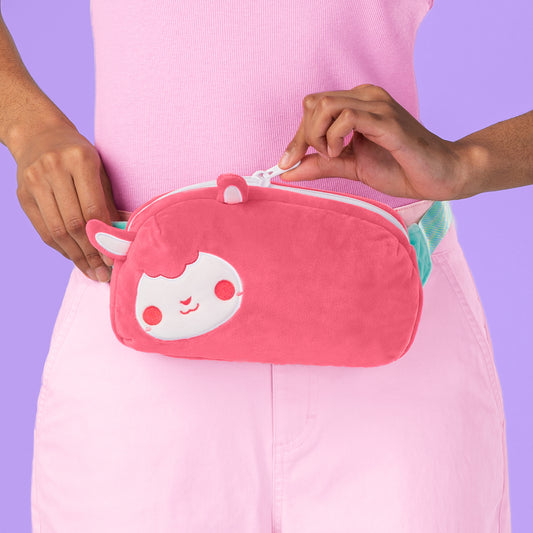 A woman holding a Plushiverse Cotton Candy Sheep Plushie Fanny Pack by TeeTurtle with an adjustable strap.