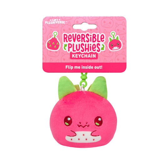 Reversible Plushiverse Dragonfruit plushie keychain packaging, featuring a round, pink plush with a cute face and green ears, labeled “flip me inside out!” on a pink background with fruit icons.