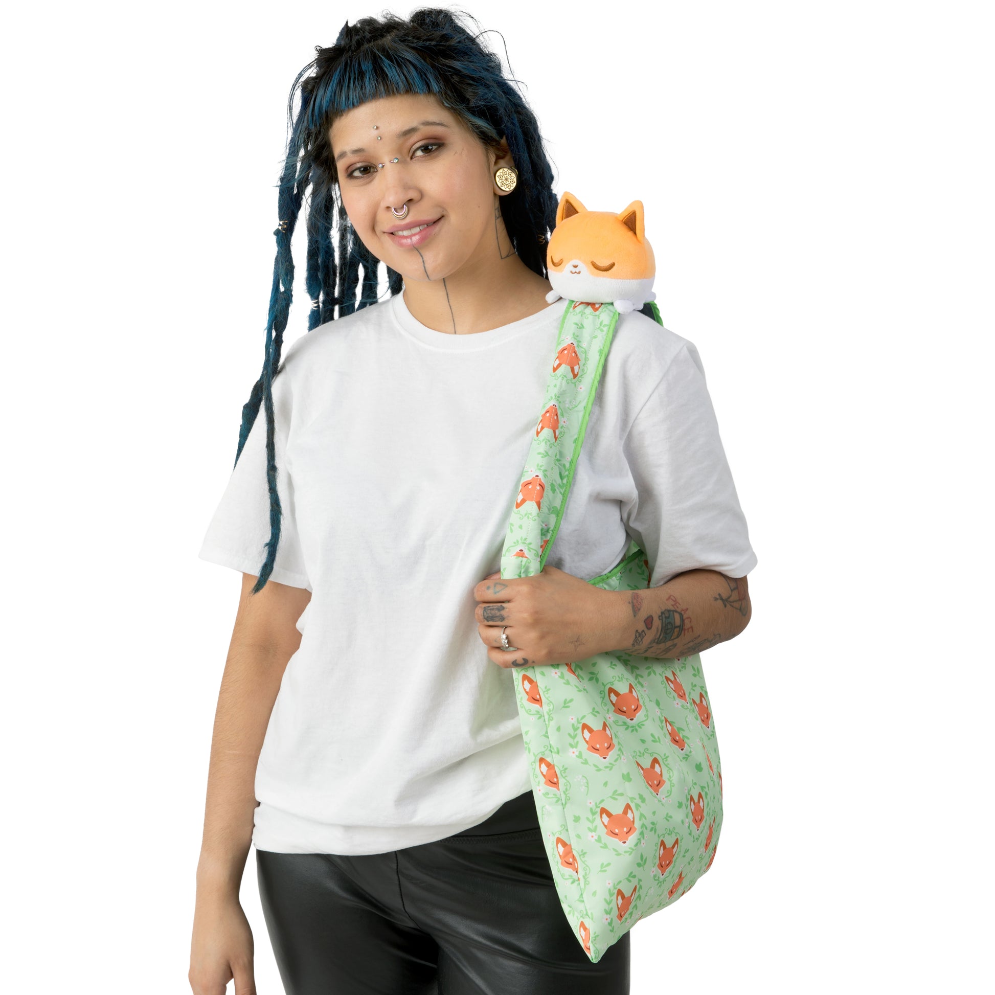 A woman with dreadlocks holding a bag with a TeeTurtle Plushiverse Floral Fox Plushie Tote Bag.