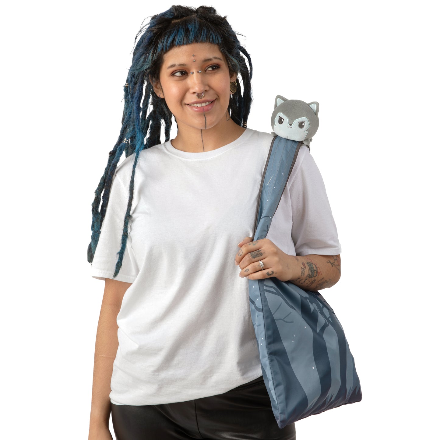 A woman with dreadlocks holding a bag with a TeeTurtle Plushiverse Moonlit Wolf Plushie Tote Bag in a storage pouch.