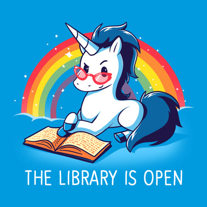 Image of a cartoon unicorn with glasses reading a book against a rainbow backdrop. The unicorn dons a cobalt blue "The Library is Open" t-shirt by monsterdigital, made from super soft ringspun cotton. Text below reads "The Library is Open.