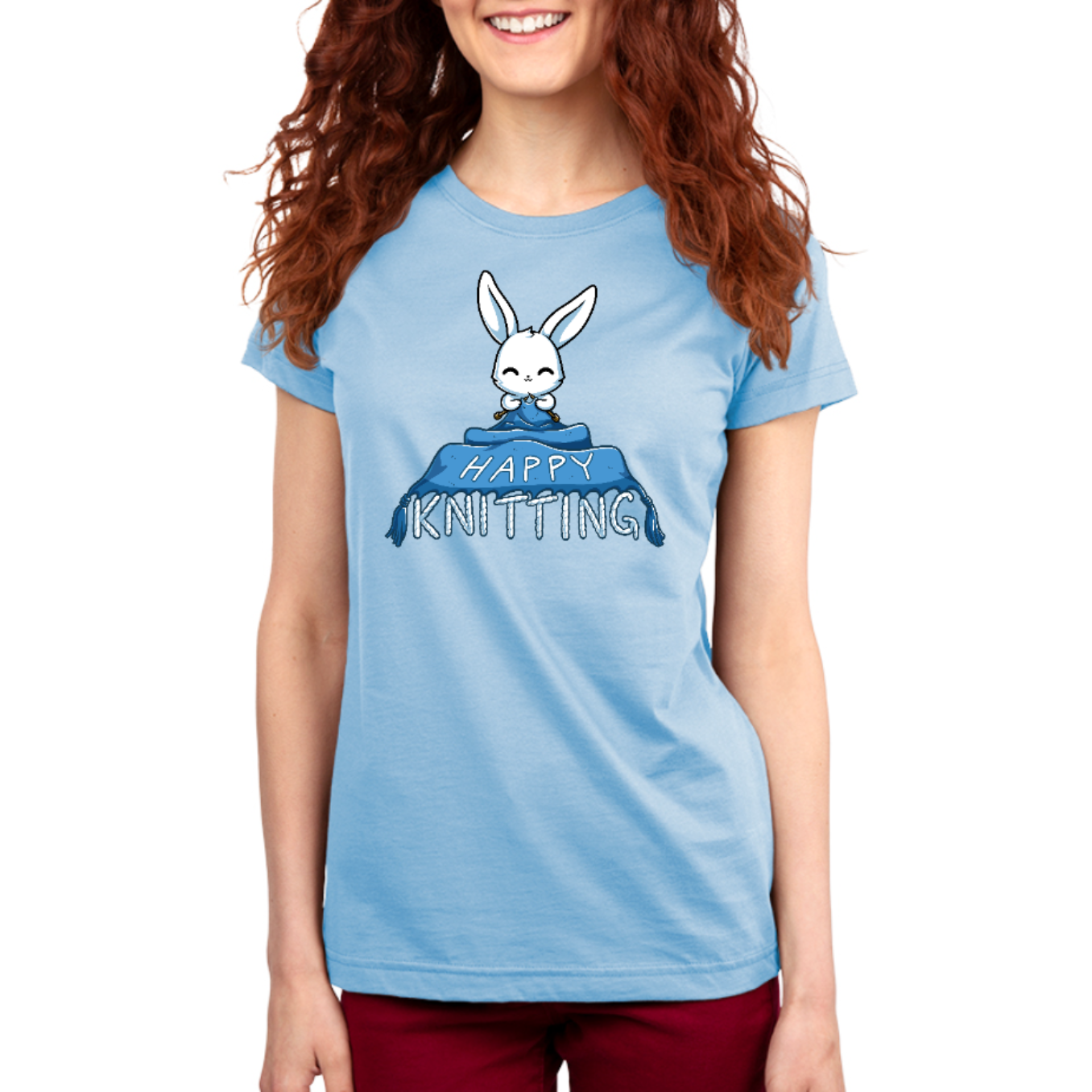 Premium Cotton T-shirt_TeeTurtle light blue Happy Knitting apparel featuring a bunny knitting a large blue blanket whose tassels end in the knitted words, “Happy Knitting“.