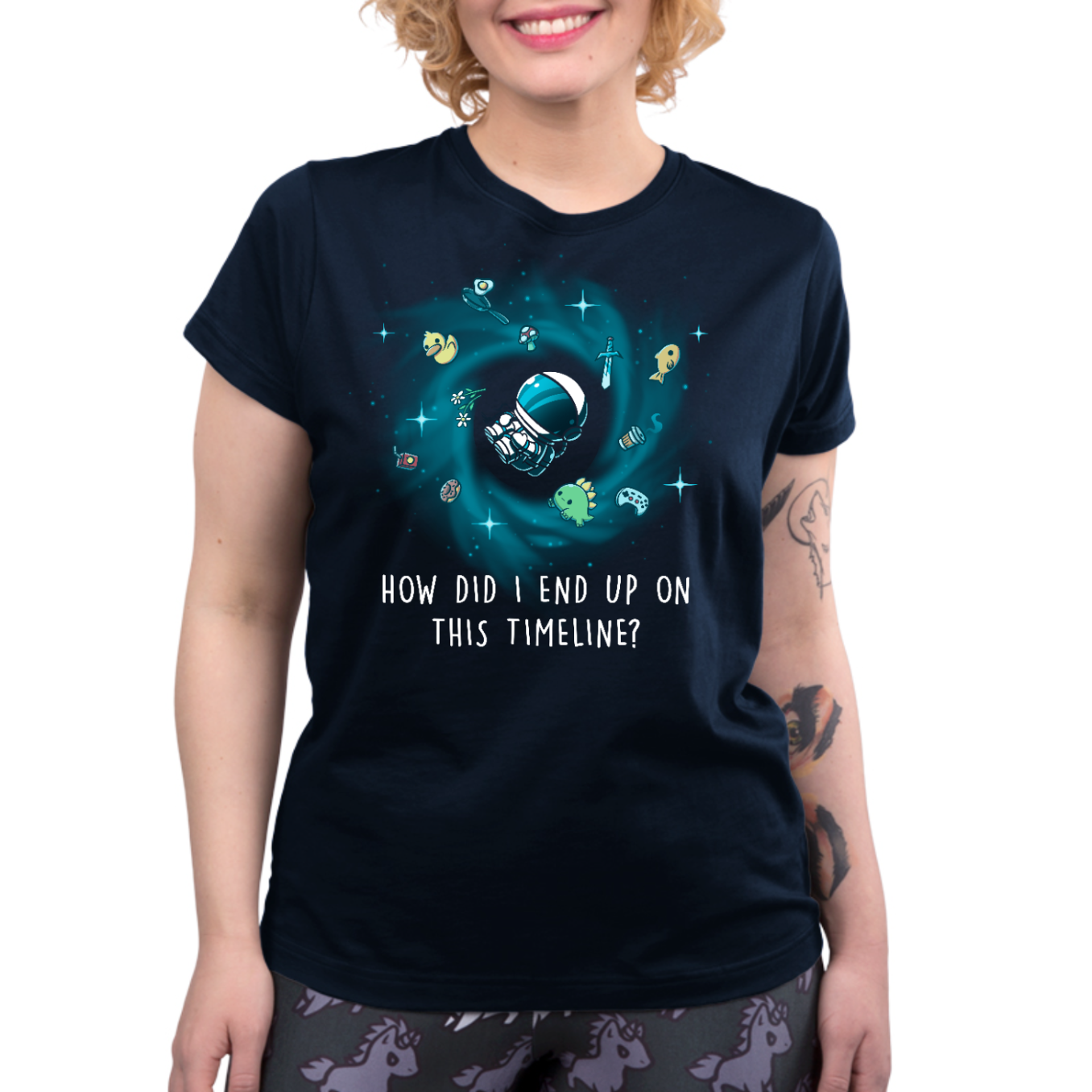 Premium Cotton T-shirt_TeeTurtle navy How Did I End Up On This Timeline Premium Cotton T-shirt featuring an astronaut floating in the middle of a black hole surrounded by random objects like a sword, frying pan, rubber duck, and game controller. Below the illustration the text rreads "How Did I End Up On This Timeline?"