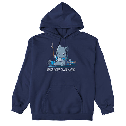 Pullover Hoodie_Teeturtle Make Your Own Magic Navy Blue Featuring a gray cat sitting in front of a book next to yarn with a wand-like stick and a crafted scarf with the text 'Make Your Own Magic' below.