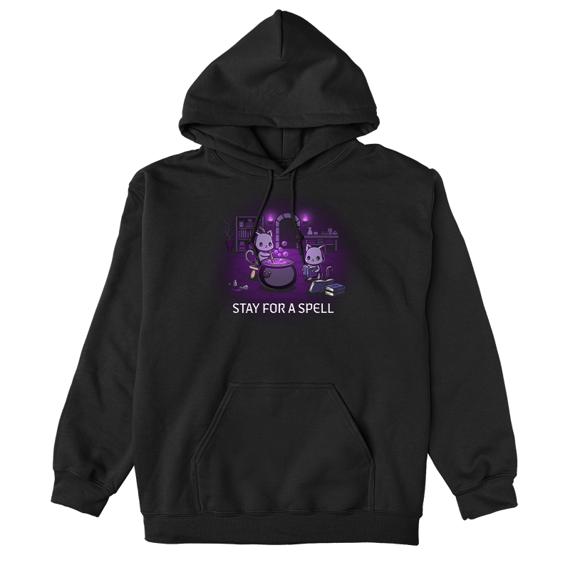 Pullover Hoodie_TeeTurtle black Stay For A Spell apparel featuring two black cats in a spooky dungeon with one cat on a stool stirring a large cauldron, and the other cat reading from a pile of spell books with books, witchcraft accessories, and potion-making equipment in the background.