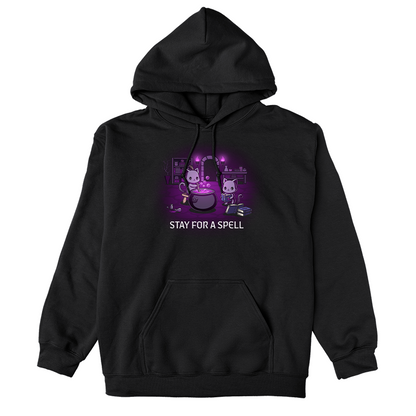 Pullover Hoodie_TeeTurtle black Stay For A Spell apparel featuring two black cats in a spooky dungeon with one cat on a stool stirring a large cauldron, and the other cat reading from a pile of spell books with books, witchcraft accessories, and potion-making equipment in the background.