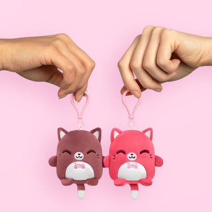 Two magnetic hands holding a Plushiverse Fancy Feline Plushmates Besties keychain, perfect for bag charms from TeeTurtle.