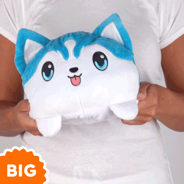 A woman is holding a TeeTurtle Big Reversible Husky Plushie toy.