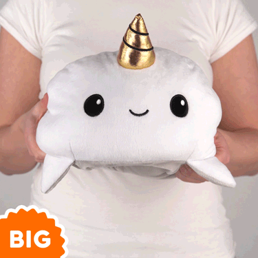 A woman is holding a TeeTurtle Big Reversible Shark & Narwhal Plushie with a gold horn.