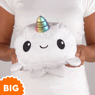 A woman is holding a big TeeTurtle Big Reversible Narwhal Plushie from TeeTurtle.