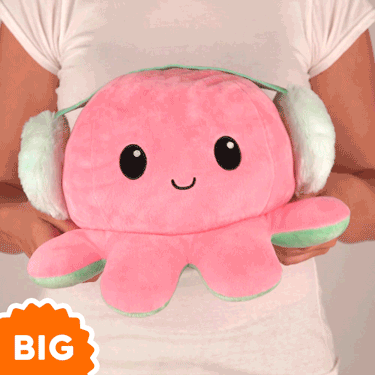 A woman is holding a TeeTurtle Big Reversible Octopus Plushie (Earmuffs) in pink.