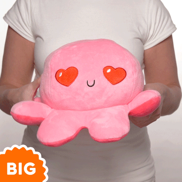 A woman is holding a TeeTurtle Big Reversible Octopus Plushie (Red + Pink), featuring a pink color.