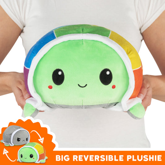 A woman holding a TeeTurtle Big Reversible Turtle Plushie (Rainbow Shell) from TeeTurtle.