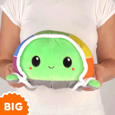 A woman is holding a green TeeTurtle Big Reversible Turtle Plushie (Rainbow Shell) with the words big turtle.