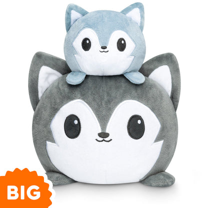 Two plush toys resembling foxes. A smaller light blue fox sits on top of a larger gray one. An orange label at the bottom left corner reads "BIG." Ideal for fans of mood plushies, these cuddly companions are perfect for adding charm to any space. This is the TeeTurtle Big Reversible Wolf Plushie (Gray) by TeeTurtle.