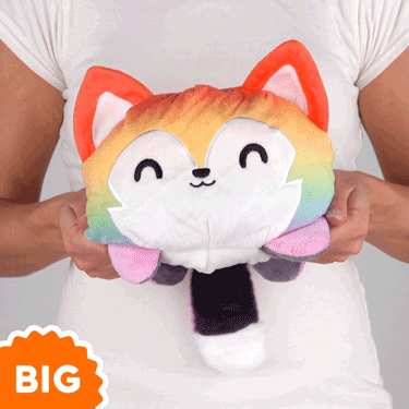 A woman is holding a TeeTurtle Big Reversible Wolf Plushie (Rainbow + Dark Gray) from TeeTurtle.