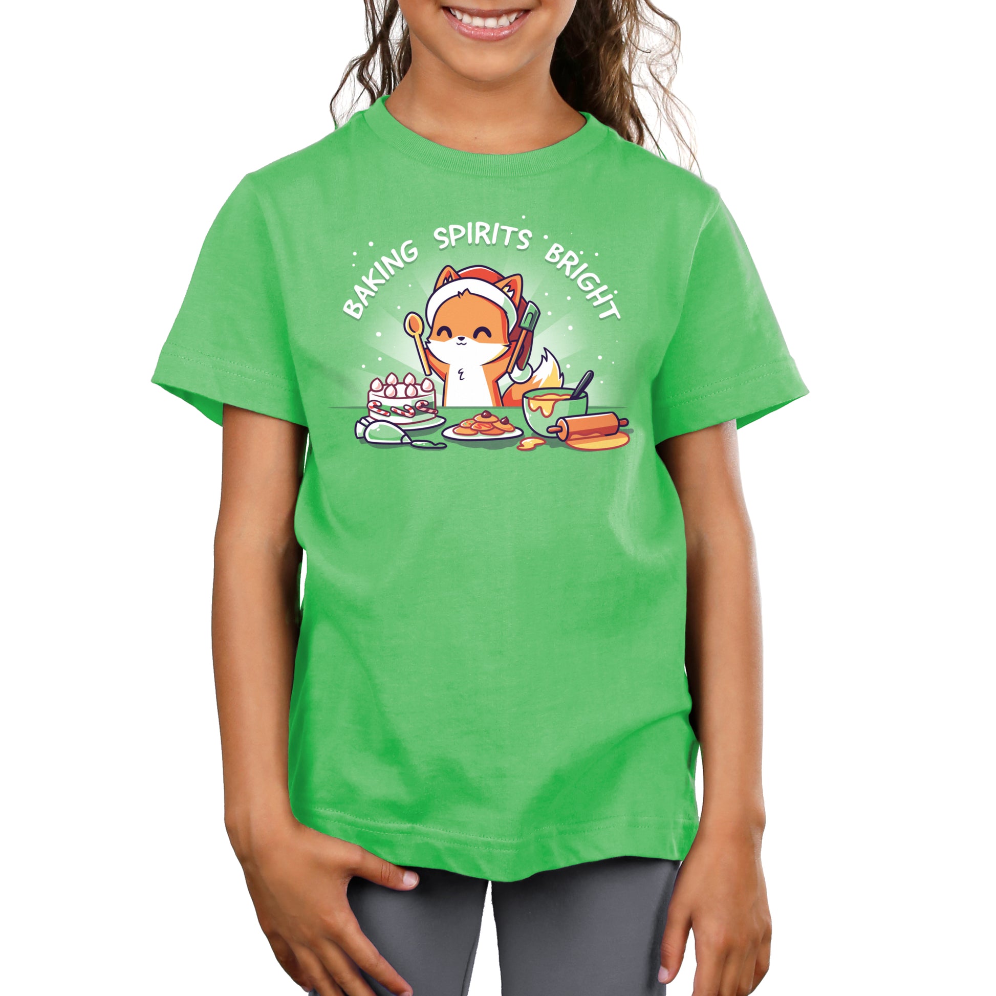 Premium Cotton T-shirt - Child wearing an apple green apparel made of super soft ringspun cotton, with a festive baking illustration and the text "Baking Spirits Bright" by monsterdigital, smiling while holding their hands clasped.