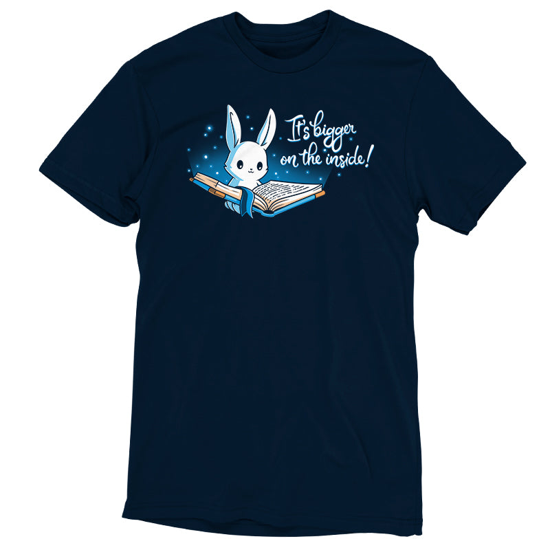 Premium Cotton T-shirt_Teeturtle Books are Bigger on the Inside Navy Blue t-shirt featuring a white rabbit reading a book from which light and sparkles are coming out with a blue ribbon bookmark marking the page with the text "It's bigger on the inside!" written next to it.