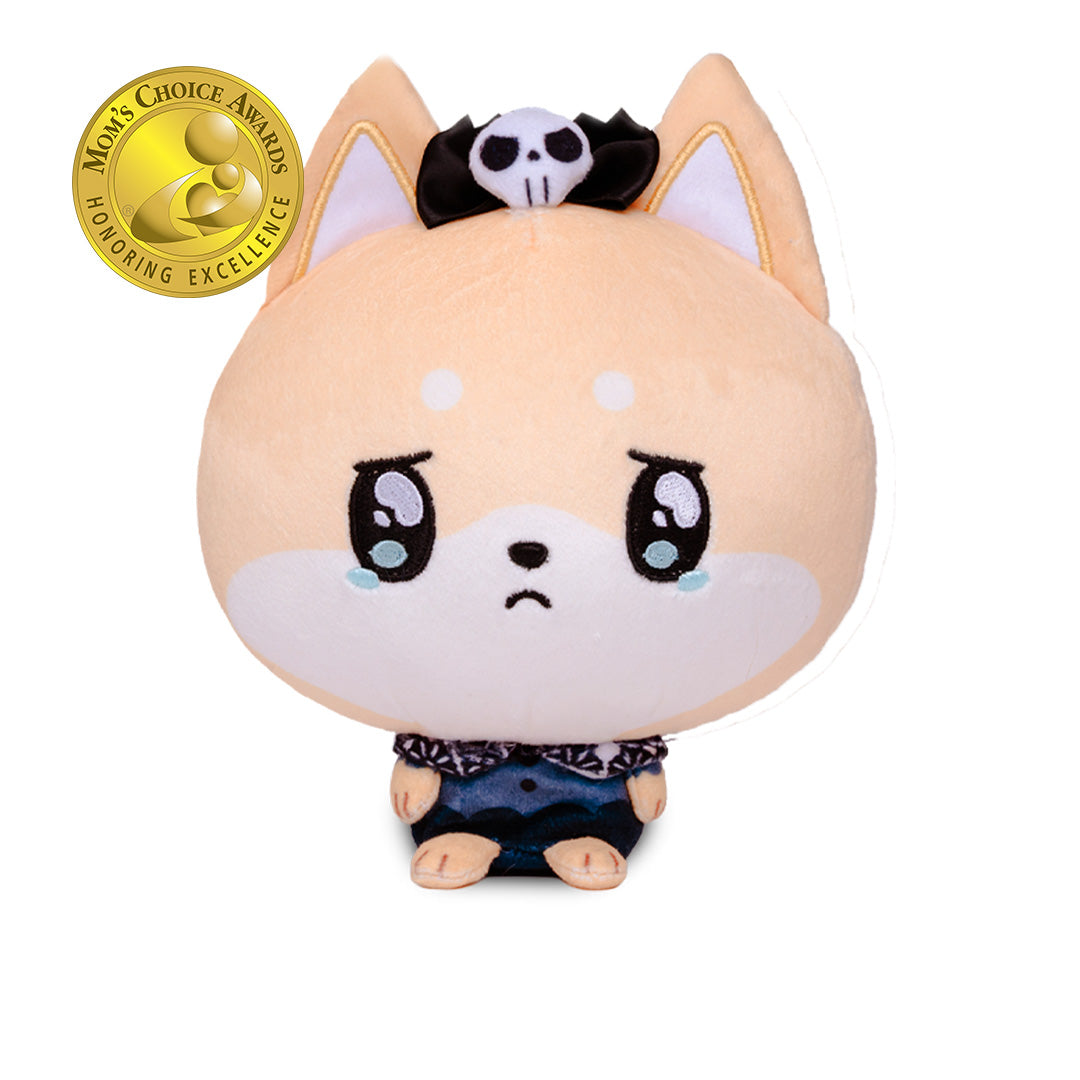 A cute plush toy of a crying Shiba Inu dog with peach-colored fur, large teary eyes, and a sad expression. It wears a black and white skull-and-crossbones headband and a dark blue patterned shirt.