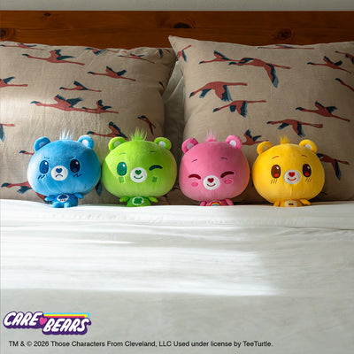 All four Care Bears Cloudheads (Grumpy Bear, Good Luck Bear, Cheer Bear, Funshine Bear) tucked into a cozy bed. 