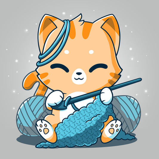 A TeeTurtle Crochet Kitty wearing a silver t-shirt, holding a knitting needle and yarn.