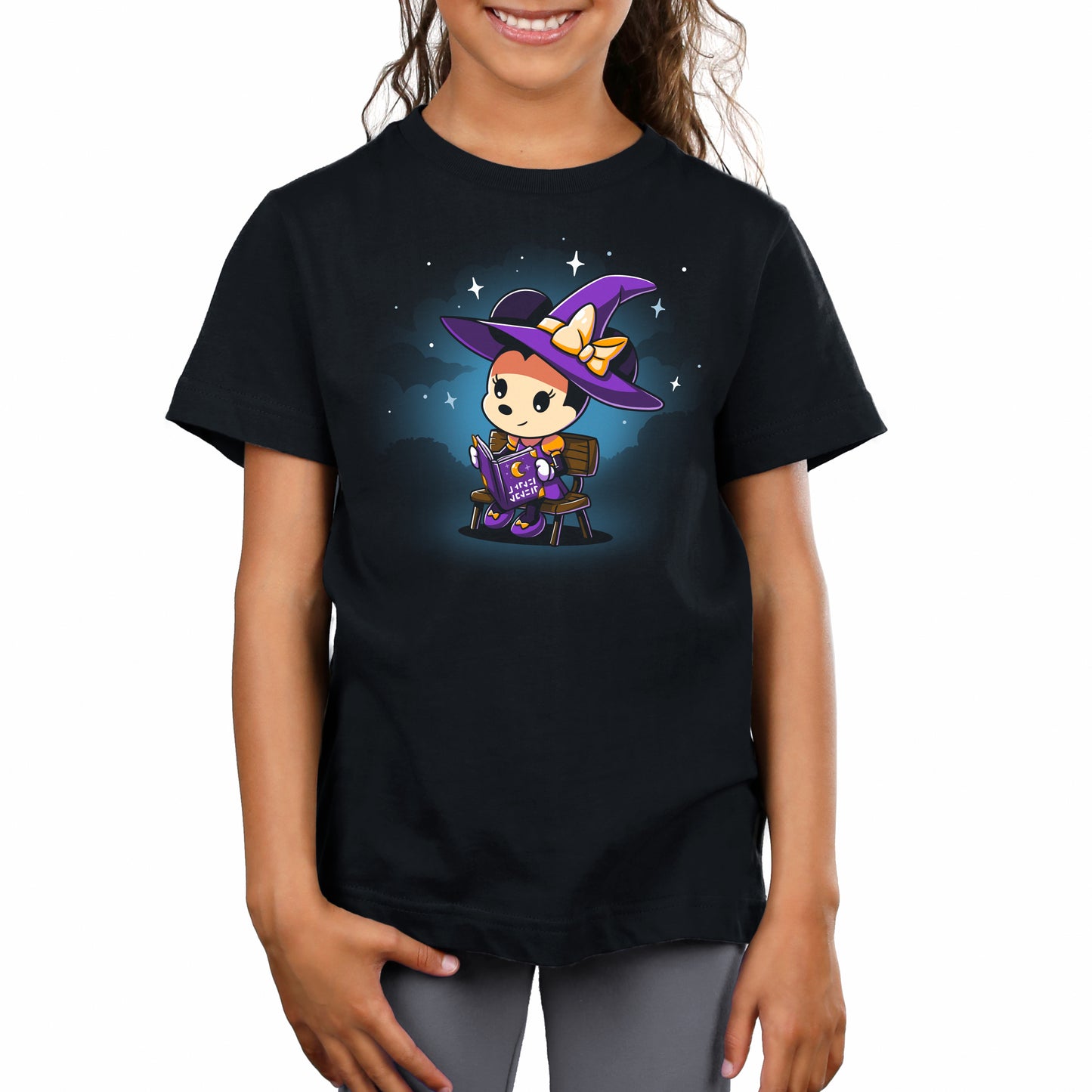 A girl wearing a black T-shirt with a Minnie's Spellbook design from Disney.