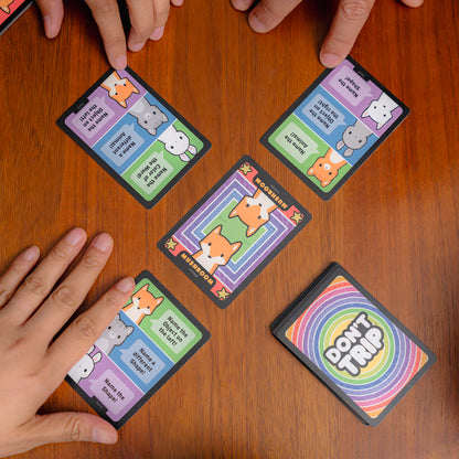The "Don't Trip" base game by Unstable Games features cartoon animals on the box all staring at the viewer, with psychedellic rainbow cocentric circles behind them and the game title in the center. "Don't Trip" is a fast-paced party game that puts players' attention to detail to the test.