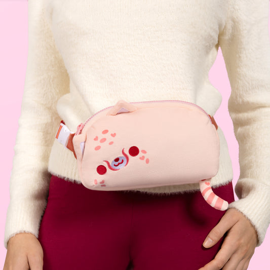 A woman wearing a pink Plushiverse Wild About You Cheetah Plushie Fanny Pack, featuring an adjustable belt for hands-free functionality by TeeTurtle.