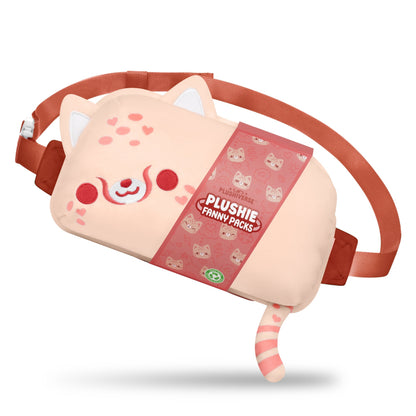 The Plushiverse Wild About You Cheetah Plushie Fanny Pack by TeeTurtle is designed like a cute, blushing cat with ears, a tail, and a happy expression. The pack features hands-free functionality and an adjustable belt in a pink and red color scheme with a tag that reads "Plushie Fanny Packs.