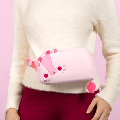 A woman is holding a Plushiverse Blushing Giraffe Plushie Fanny Pack by TeeTurtle.