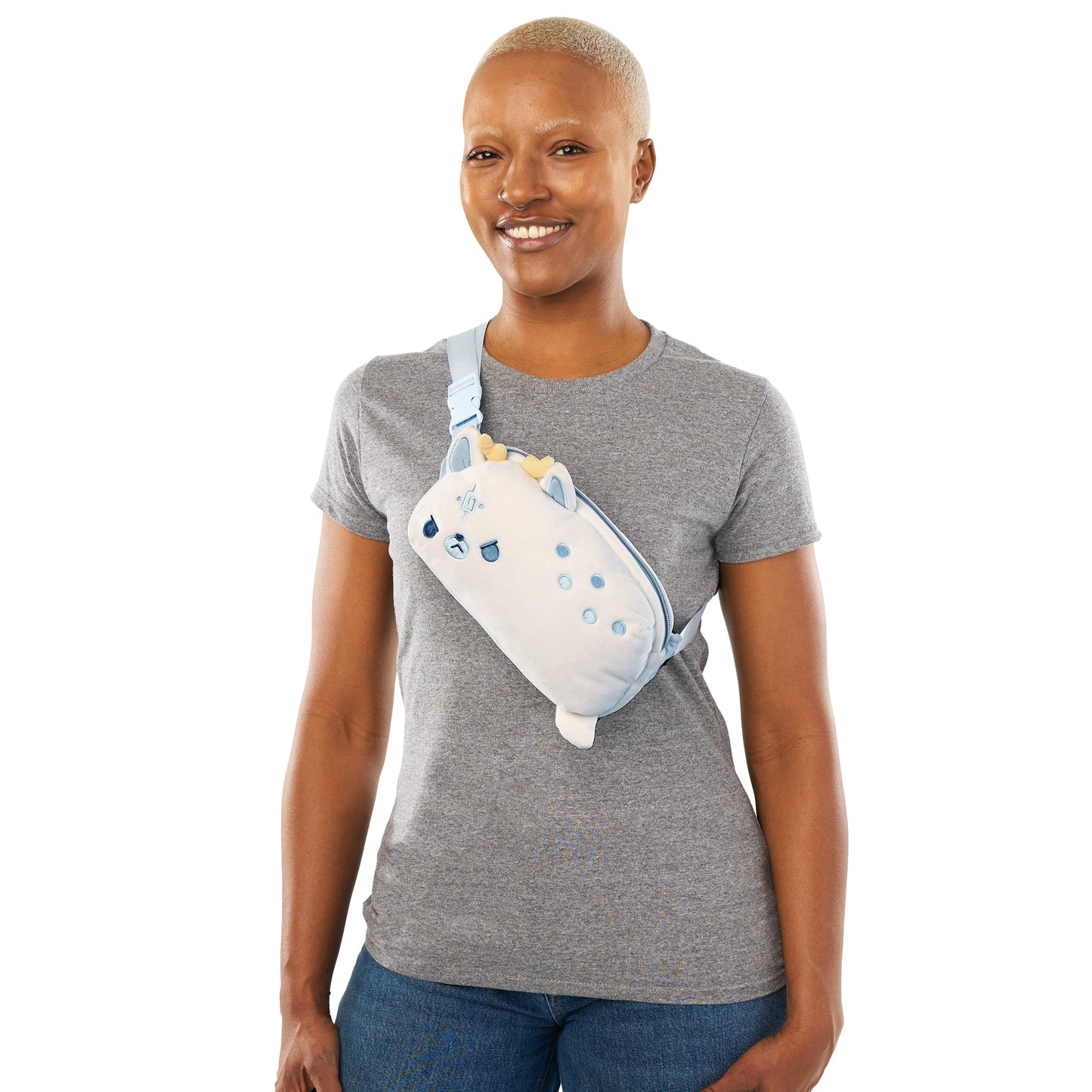 A smiling woman with a bald head wearing a gray t-shirt and a small Plushiverse White Stag Fanny Pack by TeeTurtle on her shoulder.