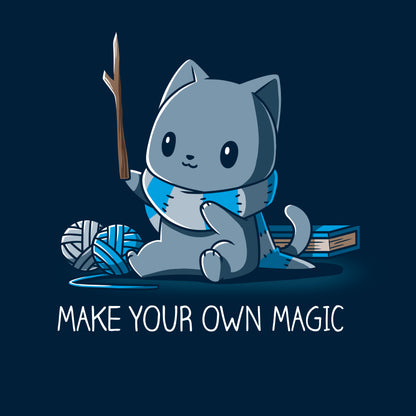 Classic Cotton T-shirt_Teeturtle Make Your Own Magic Navy Blue Featuring a gray cat sitting in front of a book next to yarn with a wand-like stick and a crafted scarf with the text 'Make Your Own Magic' below.