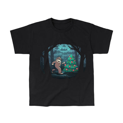 Classic Cotton T-shirt_TeeTurtle black Bigfoot Christmas apparel featuring a sasquatch caught putting holiday decor on a tree in the middle of a snowy forest.