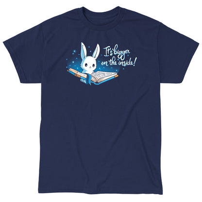 Classic Cotton T-shirt_Teeturtle Books are Bigger on the Inside Navy Blue t-shirt featuring a white rabbit reading a book from which light and sparkles are coming out with a blue ribbon bookmark marking the page with the text "It's bigger on the inside!" written next to it.