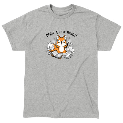 Classic Cotton T-shirt_A cartoon fox enthusiastically holding drawing tools, surrounded by sketchbooks with various drawings. Text above reads "Draw All The Things!" This monsterdigital original Draw all the Things! is crafted from super soft ringspun cotton for ultimate comfort.