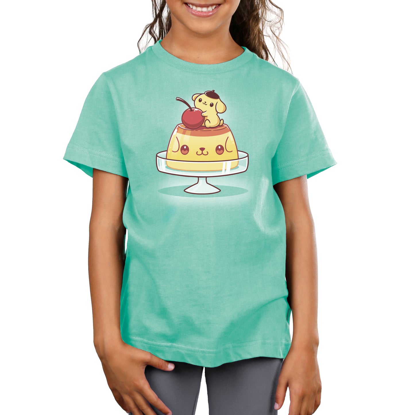 A girl wearing a green Sanrio women's t-shirt with an image of Pompompurin's Pudding on top of a cake.