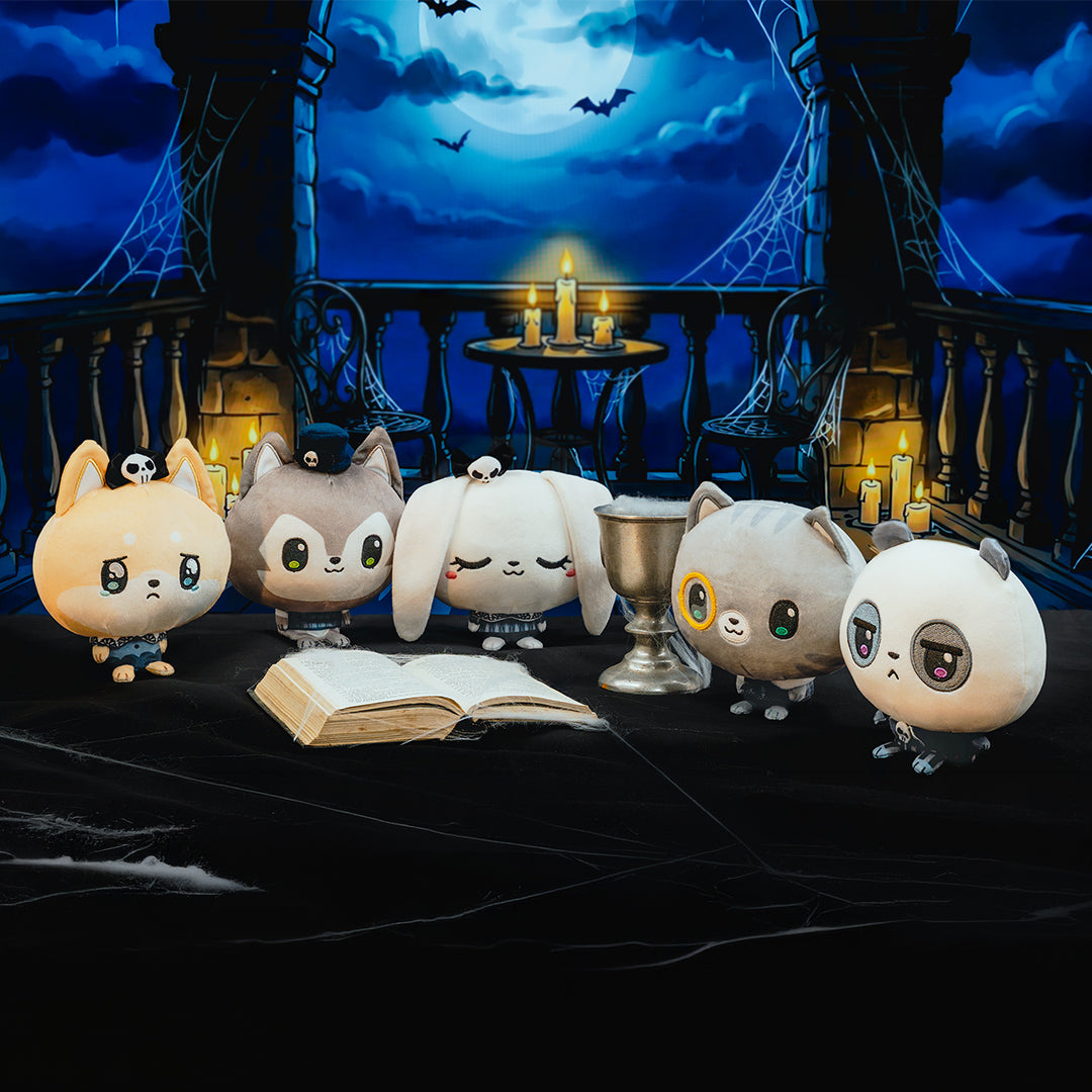 Five cute animal characters stand on a dark table in a gothic night scene with candles, bats, and a moonlit sky.
