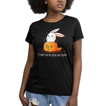 A woman wearing a TeeTurtle "What's on the Inside (Glow)" black t-shirt with a spooky image of a bunny in a pumpkin.