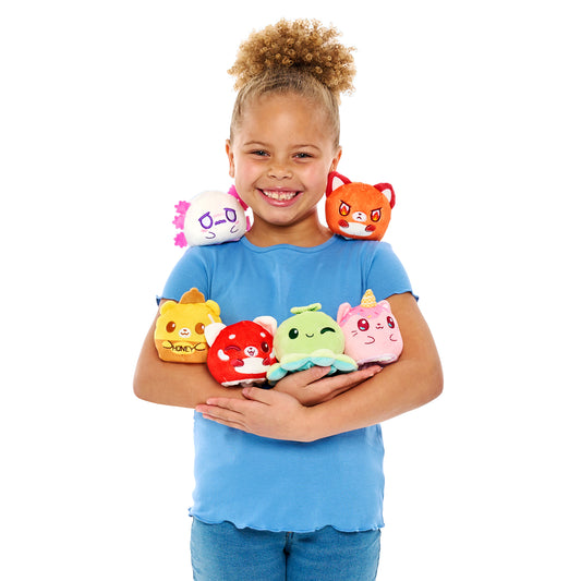 A young girl smiling while holding multiple colorful plushies, including a Plushiverse Kawaii Cuties Reversible Plushie Mystery Box from TeeTurtle.