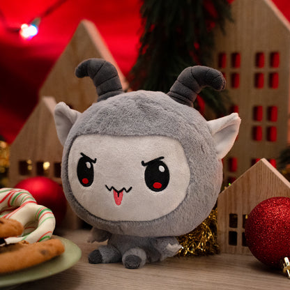 Cloudheads: 5" Krampus facing to the left, and surrounded by holiday items, such as a torn-up present box, wrapping paper, chocolate chip cookies, pretzels, tree branches, Christmas lights and tree ornaments.