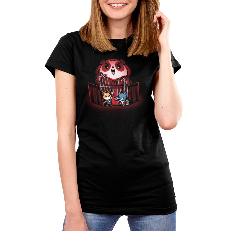 Premium Cotton T-shirt_TeeTurtle Puppet Master black t-shirt featuring an illustration of a cartoon panda smiling evilly and standing behind a puppet  theater holding a fox puppet with a sword in the left hand and a cat with an axe and shield in the right hand. The illustration is being illuminated by a red glow.