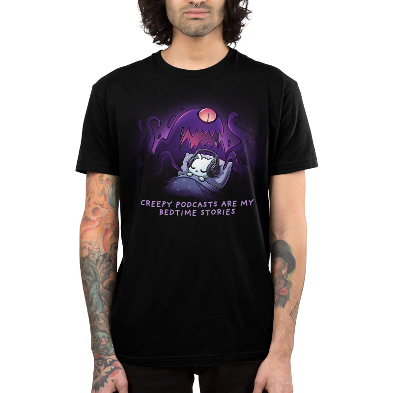 Premium Cotton T-shirt_TeeTurtle black Creepy Podcasts Are My Bedtime Stories apparel featuring a cat lying down in bed cozily wearing headphones with a giant purple monster looming over it and waving its tentacles.