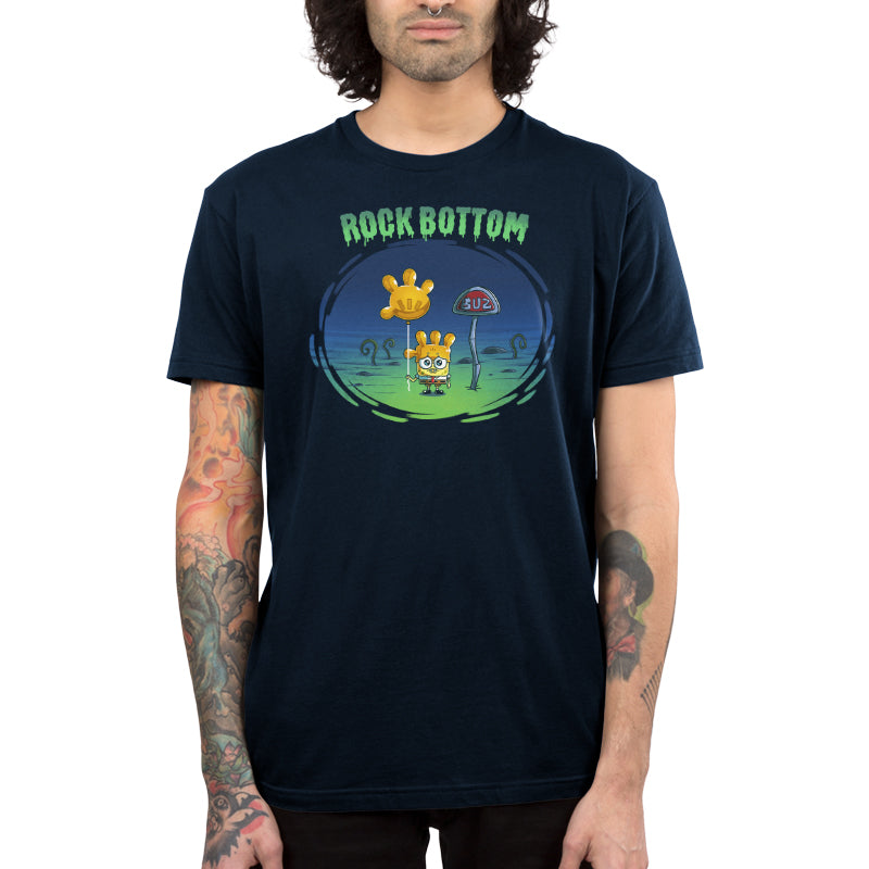 Premium Cotton T-shirt_TeeTurtle navy blue SpongeBob Rock Bottom apparel featuring SpongeBob Square Pants holding a yellow balloon that looks like a four fingered hand while wearing a second simliar balooon on his head as a hat. He looks sad and he's next to a "Buz" sign.The words "Rock Bottom" are on top in green and they look like they are melting or dripping. 