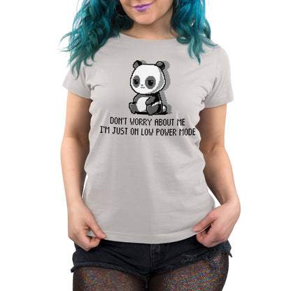 Person wearing a light gray unisex tee made of super soft ringspun cotton, featuring a pixelated panda and the text "Don't worry about me, I'm just on Low Power Mode" by monsterdigital. The person has blue hair and is also sporting dark shorts.