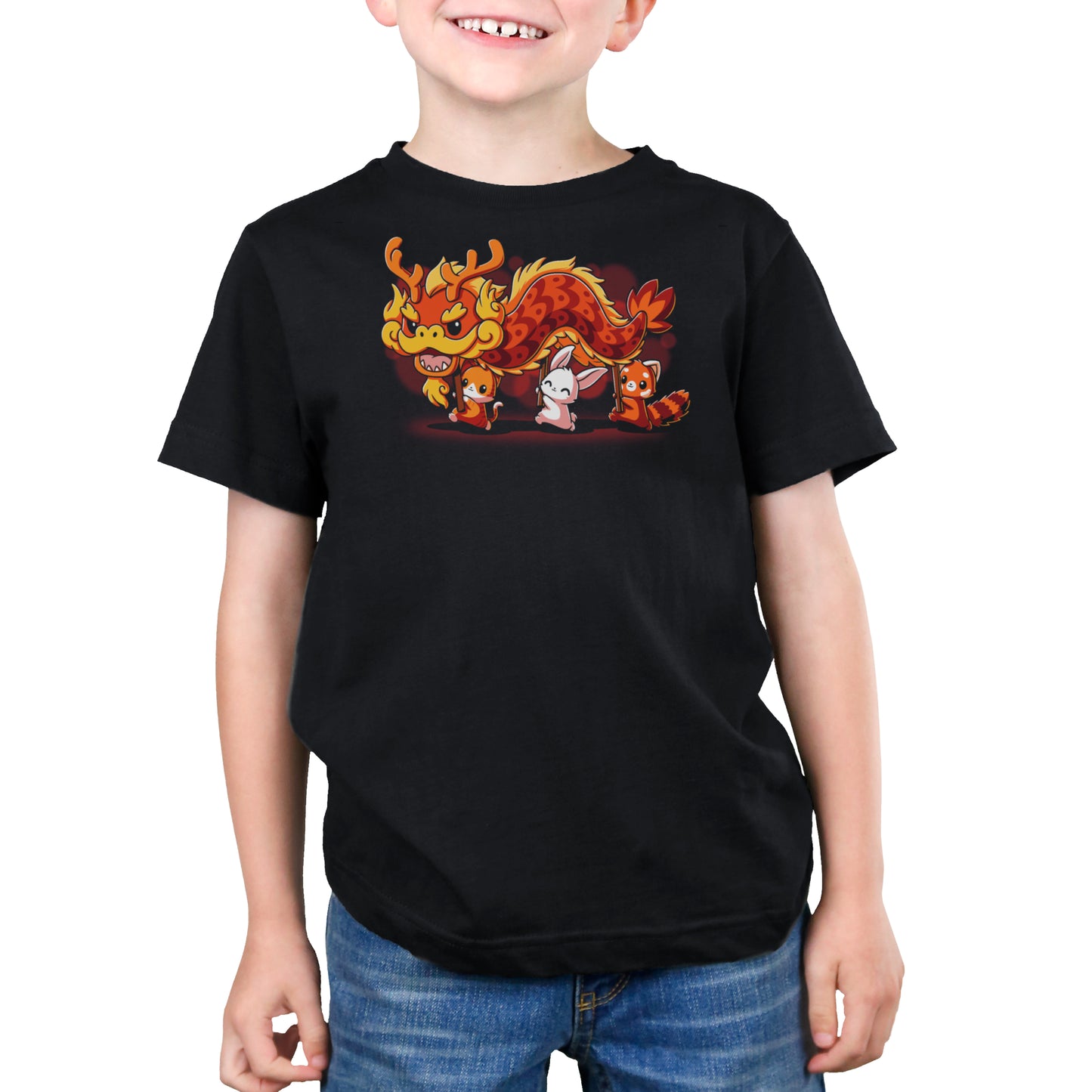A child wearing monsterdigital's The Dragon Dance, a black unisex tee with a cartoon dragon and a small character design on the front, made from super soft ringspun cotton, paired with blue jeans, smiling and standing against a plain white background.