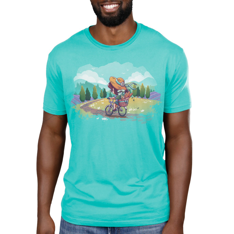 Premium Cotton T-shirt_TeeTurtle Countryside Biking Caribbean blue t-shirt featuring an illustration of a girl biking on a path in the countryside with bread and flowers in her basket. The path winds through rolling hills and fields of grass with small, white flowers. Green trees line the sides of the path, and lavender bushes are behind the trees, set against a light teal/turquoise sky, with fluffy white clouds and some birds.