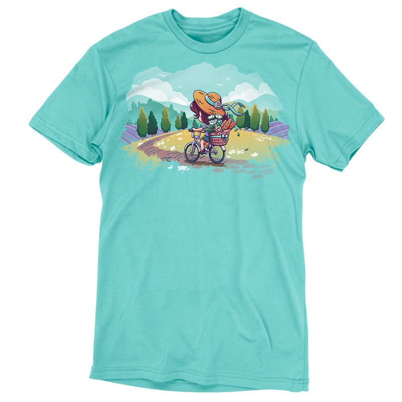 Premium Cotton T-shirt_TeeTurtle Countryside Biking Caribbean blue t-shirt featuring an illustration of a girl biking on a path in the countryside with bread and flowers in her basket. The path winds through rolling hills and fields of grass with small, white flowers. Green trees line the sides of the path, and lavender bushes are behind the trees, set against a light teal/turquoise sky, with fluffy white clouds and some birds.