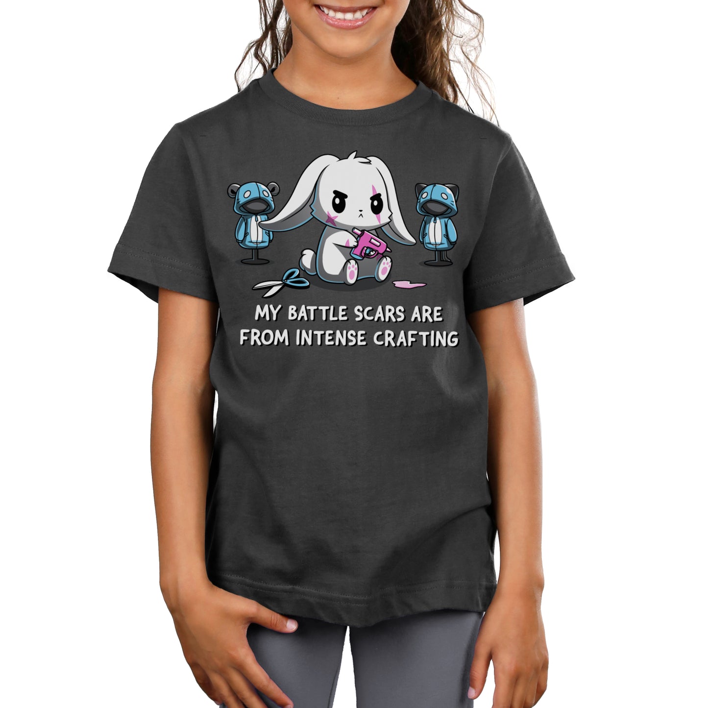 Premium Cotton T-shirt - A child wearing a charcoal gray crafting apparel featuring an illustration of a bunny sewing stuffed animals. Made from super soft ringspun cotton, the apparel text reads, "My battle scars are from intense crafting." The product is "Battle Scars" by monsterdigital.
