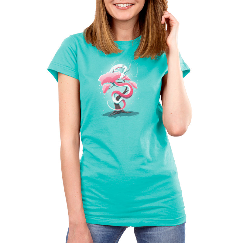 Woman wearing a Caribbean Blue T-shirt featuring an artistic design of intertwined, pink and white elements. She is smiling and standing against a plain white background. The T-shirt showcases the Cherry Blossom Dragon by monsterdigital.